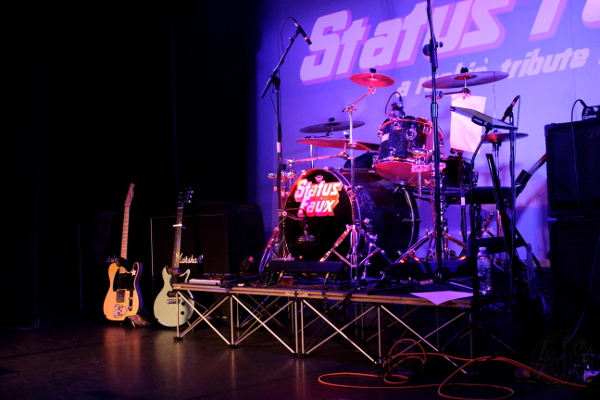 Status Faux stage set up with musical instruments and backdrop.