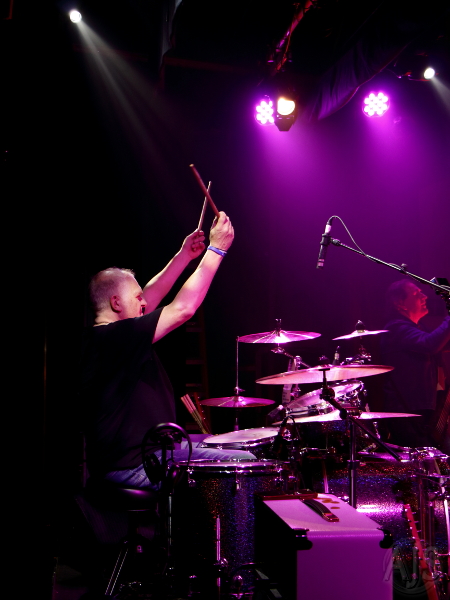 Drummer in side profile with his hands in the air counting in a song.