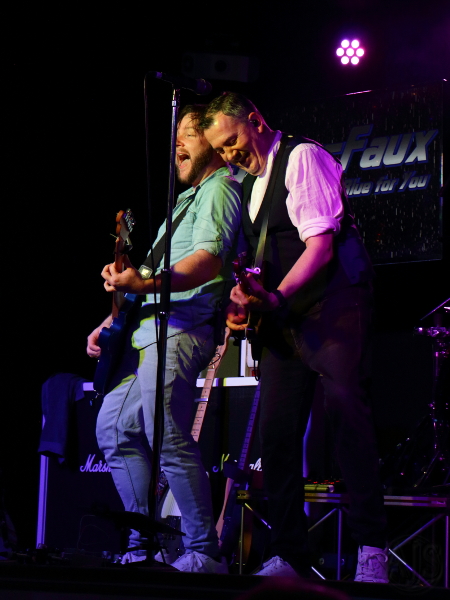The two Status Faux frontmen laughing together on stage.
